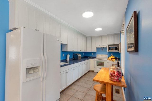 kitchen with white appliances, white cabinets, and light tile patterned flooring