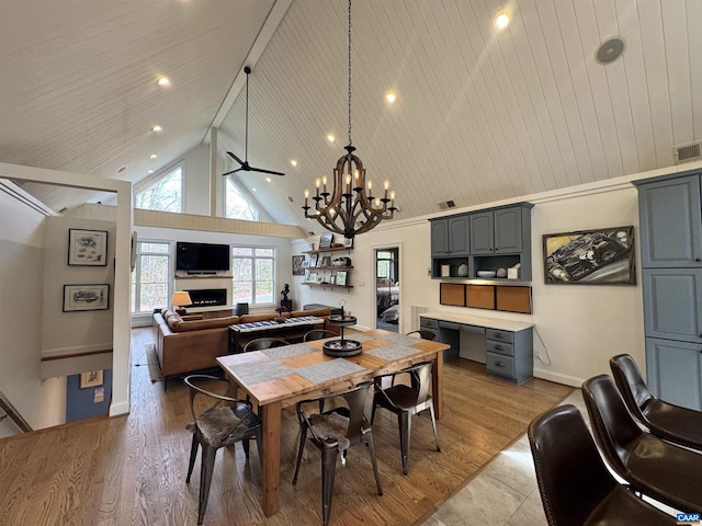 dining room with high vaulted ceiling, ceiling fan with notable chandelier, wood ceiling, and light wood-type flooring