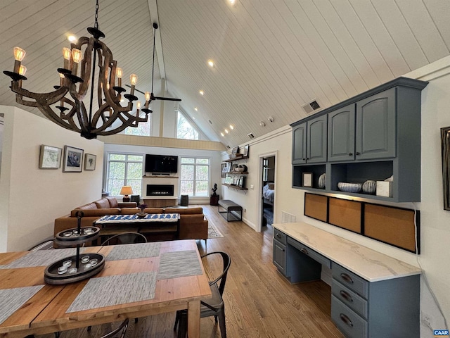 interior space with built in desk, high vaulted ceiling, a notable chandelier, light hardwood / wood-style floors, and wooden ceiling