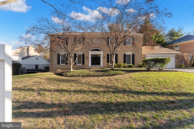 colonial-style house featuring an attached garage, driveway, and a front lawn