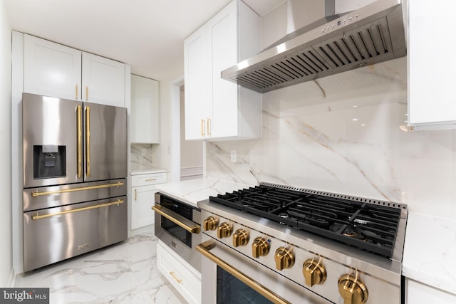 kitchen featuring light stone countertops, wall chimney exhaust hood, white cabinetry, and stainless steel appliances