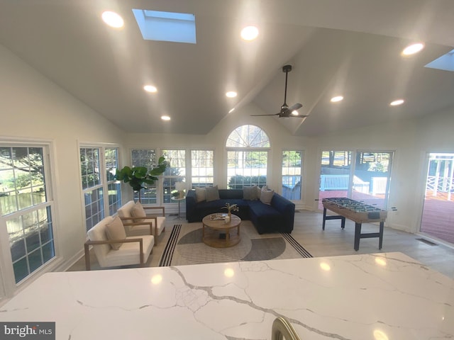 living room with a skylight, ceiling fan, light wood-style flooring, and recessed lighting