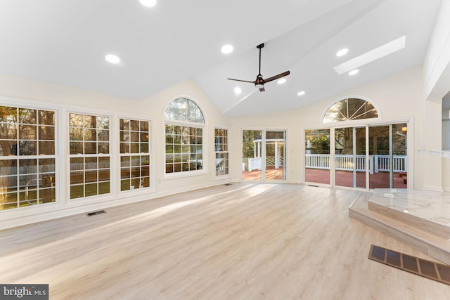 unfurnished sunroom featuring vaulted ceiling with skylight, visible vents, and a ceiling fan