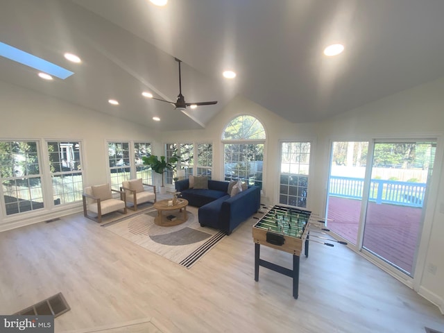 living area with vaulted ceiling with skylight, light wood-style flooring, and recessed lighting