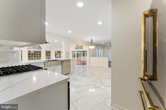 kitchen with white cabinets, marble finish floor, appliances with stainless steel finishes, light stone countertops, and decorative light fixtures