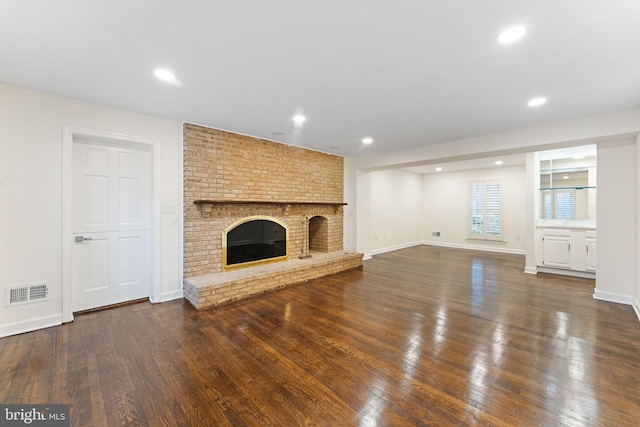 unfurnished living room featuring dark wood finished floors, a fireplace, recessed lighting, visible vents, and baseboards