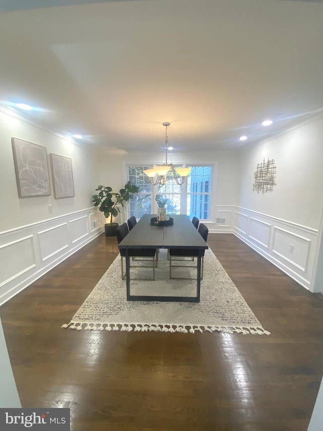 dining room with dark wood-style floors, a notable chandelier, and a decorative wall