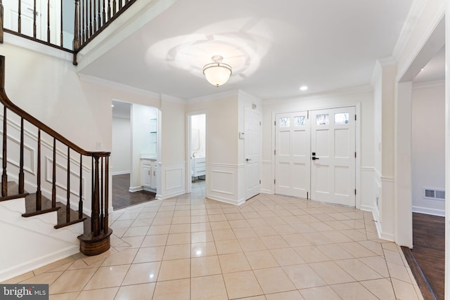 foyer entrance featuring stairs, visible vents, crown molding, and light tile patterned floors