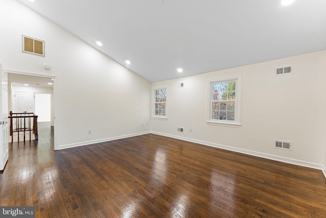 spare room featuring dark wood-type flooring, visible vents, and baseboards