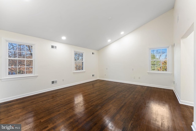 spare room featuring dark wood-style floors, visible vents, and vaulted ceiling