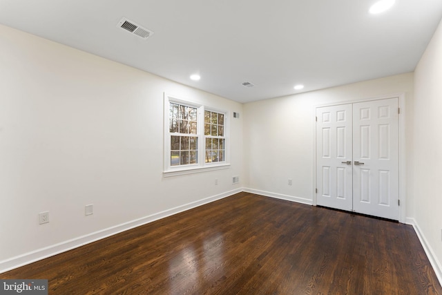 unfurnished room with baseboards, visible vents, dark wood-type flooring, and recessed lighting