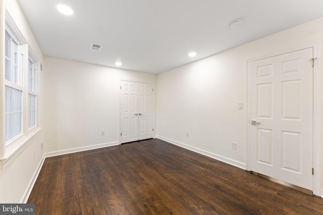 empty room featuring dark wood-type flooring, recessed lighting, visible vents, and baseboards