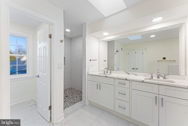 full bathroom with marble finish floor, a skylight, baseboards, and a sink