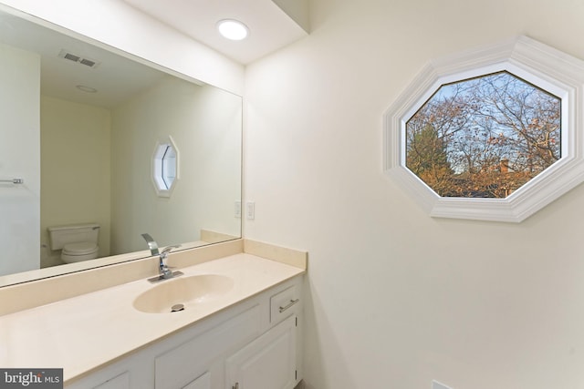 bathroom featuring a healthy amount of sunlight, visible vents, vanity, and toilet