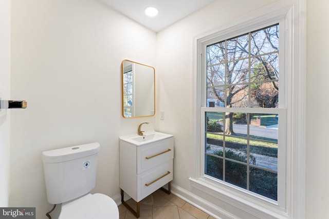 half bathroom with baseboards, vanity, toilet, and tile patterned floors