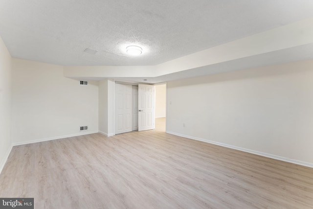 unfurnished room with baseboards, visible vents, light wood-style flooring, and a textured ceiling