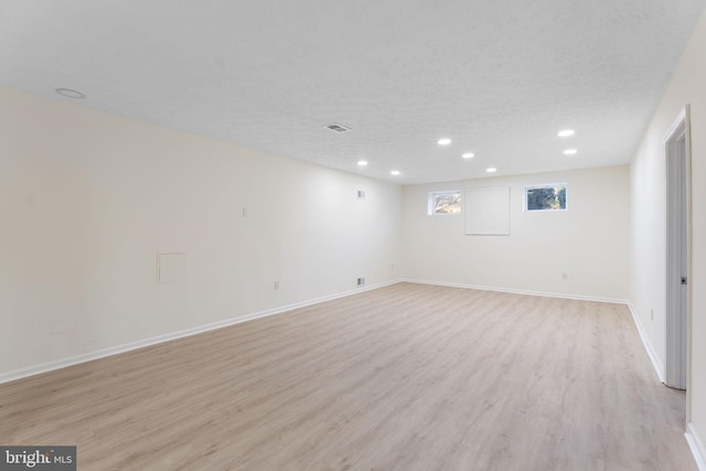 below grade area with a textured ceiling, recessed lighting, visible vents, baseboards, and light wood-type flooring