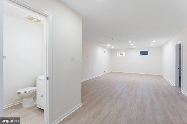 basement with light wood-type flooring, visible vents, baseboards, and recessed lighting