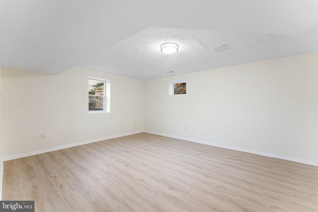 interior space featuring light wood-type flooring, baseboards, and a textured ceiling