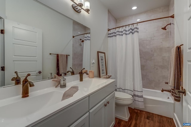 full bathroom with hardwood / wood-style floors, toilet, shower / bathtub combination with curtain, and vanity