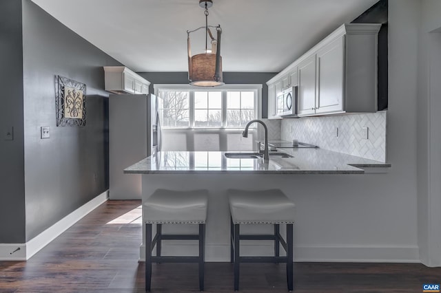 kitchen with decorative light fixtures, stainless steel appliances, a kitchen bar, and kitchen peninsula