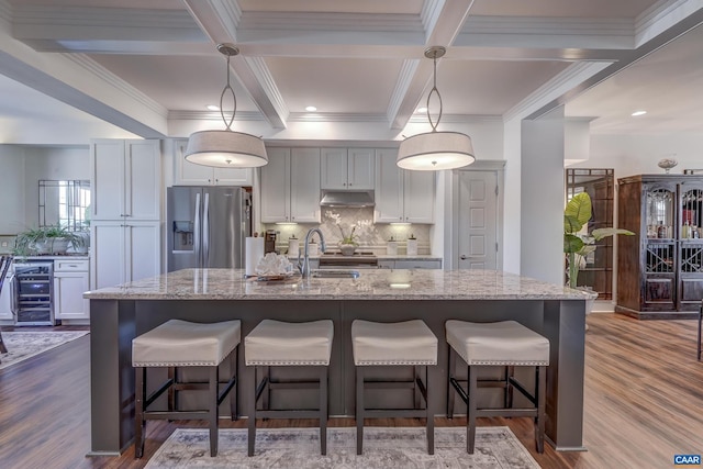 kitchen with a kitchen island with sink, hanging light fixtures, a breakfast bar area, and stainless steel appliances