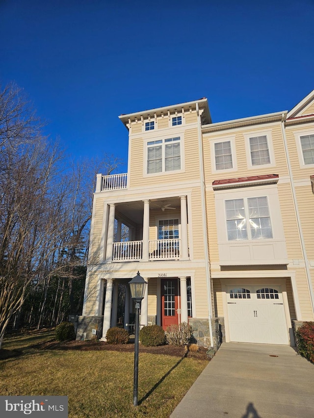 view of front of home with a balcony, a garage, concrete driveway, stone siding, and a front yard