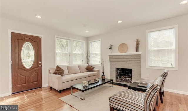 living room featuring a brick fireplace and light hardwood / wood-style flooring