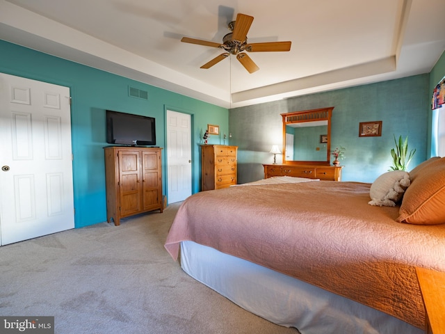 bedroom featuring light carpet, ceiling fan, and a raised ceiling