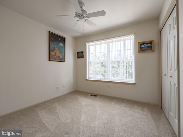 unfurnished bedroom with a closet, ceiling fan, and light colored carpet