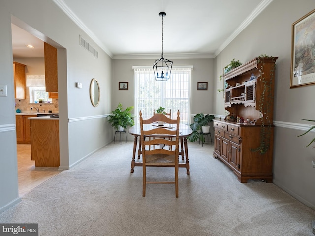 carpeted dining room featuring sink, crown molding, and an inviting chandelier