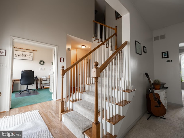 staircase featuring wood-type flooring and a high ceiling