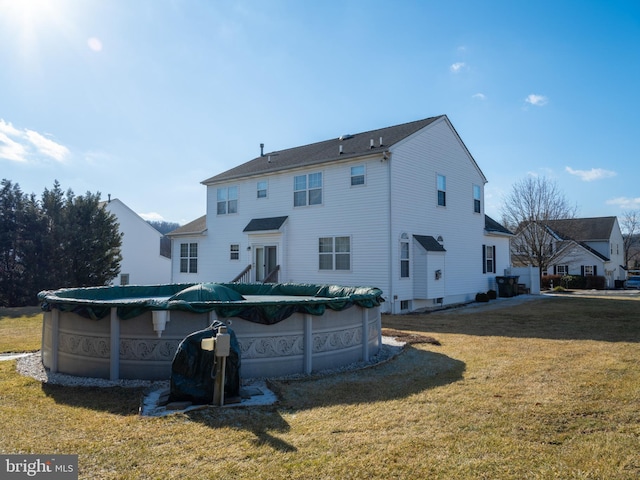 back of property with a covered pool and a yard