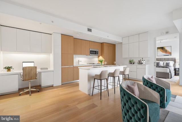 kitchen with visible vents, white cabinets, light countertops, stainless steel microwave, and modern cabinets