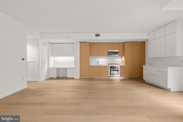 kitchen featuring appliances with stainless steel finishes, white cabinets, light countertops, and modern cabinets