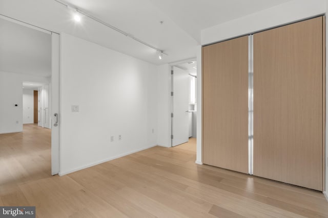 unfurnished bedroom with light wood-style floors, baseboards, and track lighting