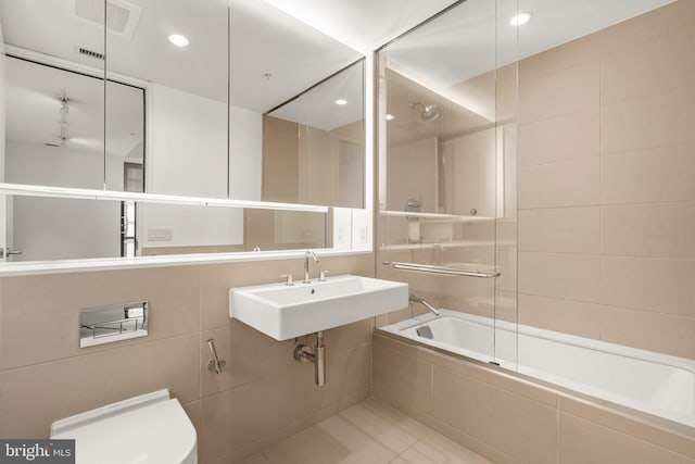 bathroom featuring tiled shower / bath combo, visible vents, toilet, and tile walls