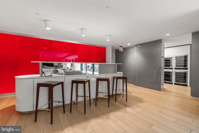 kitchen featuring beverage cooler, modern cabinets, light wood-style flooring, and recessed lighting