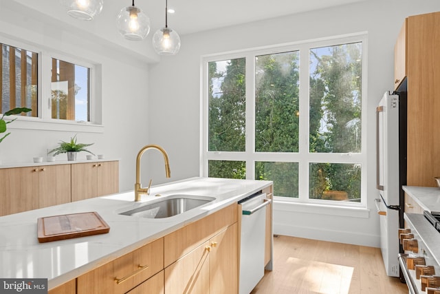 kitchen featuring sink, hanging light fixtures, white refrigerator, stainless steel dishwasher, and light stone countertops