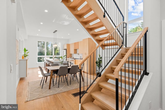 dining area with a healthy amount of sunlight, sink, light hardwood / wood-style flooring, and a notable chandelier