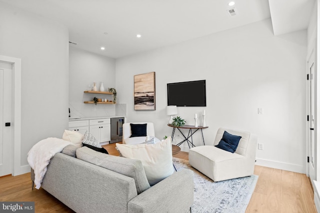 living room featuring sink, beverage cooler, and light hardwood / wood-style floors