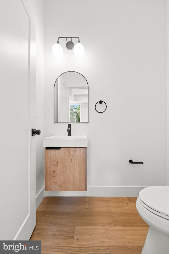 bathroom featuring wood-type flooring, toilet, and vanity