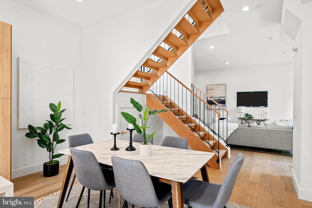 dining area featuring a towering ceiling and light hardwood / wood-style floors