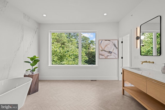 bathroom featuring vanity, parquet floors, and a bathtub