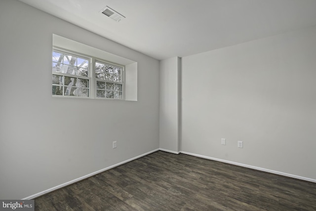 unfurnished room with dark wood-type flooring, visible vents, and baseboards