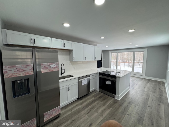 kitchen with kitchen peninsula, sink, white cabinetry, and black appliances