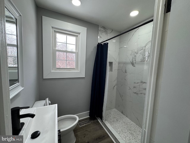 bathroom with toilet, a shower with shower curtain, plenty of natural light, and wood-type flooring