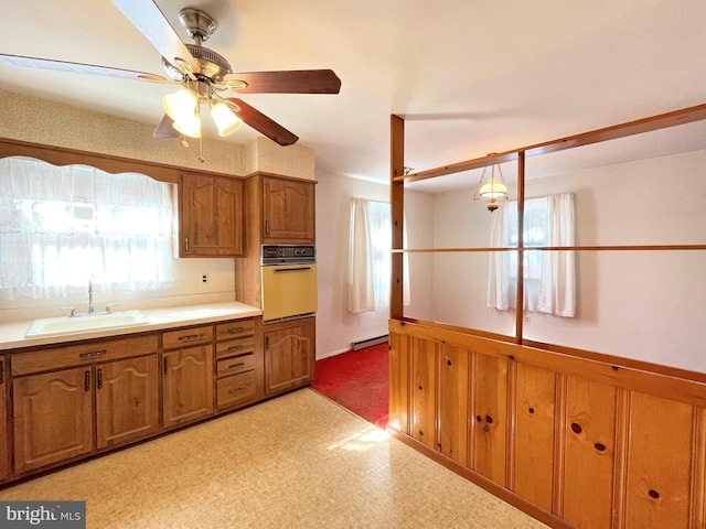 kitchen featuring baseboard heating, sink, oven, and a healthy amount of sunlight