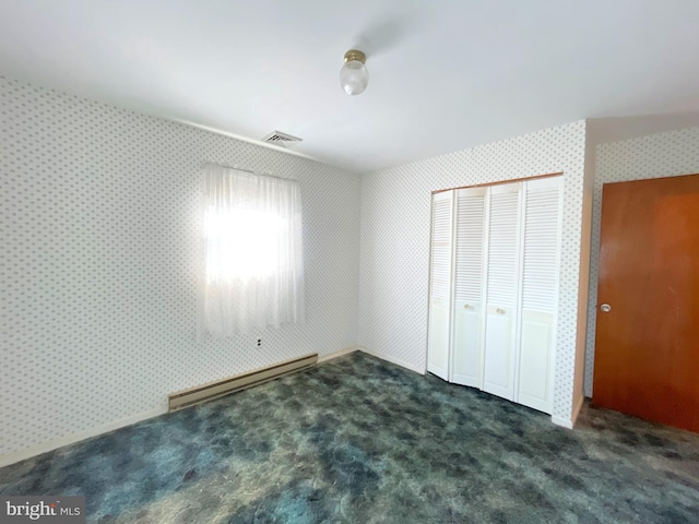 unfurnished bedroom featuring a baseboard radiator, a closet, and dark carpet