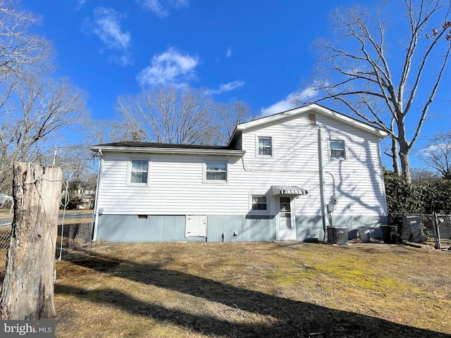 back of house with cooling unit and a lawn